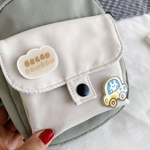 Detailed close-up of sage green canvas mini crossbody bag with cute bunny brooch