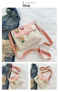 Détail du sac bandoulière en toile rose et beige avec écussons d'ours et bandoulière