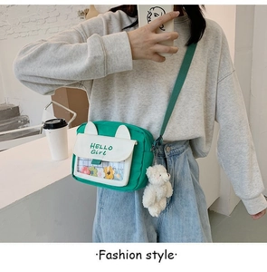 Detail of green canvas crossbody bag with cat ears, floral pocket, and bear pendant