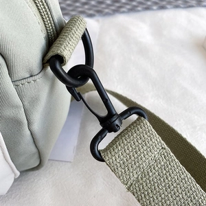 Close-up of durable D-ring buckle and reinforced nylon stitching on green crossbody bag