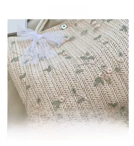 Détail du sac en paille beige avec broderie florale et nœud en dentelle blanche