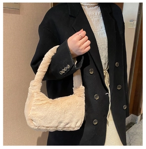 Detail showing the fluffy cream faux fur texture of the shoulder bag on a black coat