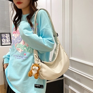 Beige nylon crescent moon crossbody bag with adjustable strap and small tiger charm