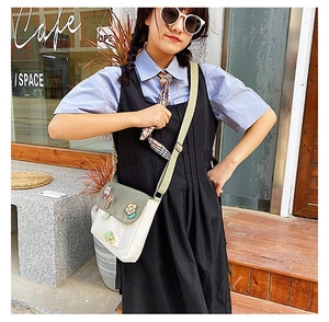 Détail du sac bandoulière en toile avec broderie chat et sangle verte réglable