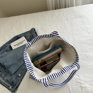 Large blue and white striped canvas tote bag showing spacious interior with personal items