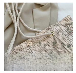 Détail du sac en paille avec broderie florale, boucle magnétique et nœud en dentelle