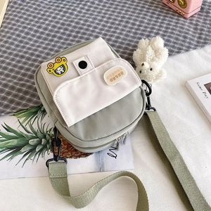 Close-up of mini green canvas crossbody bag with cute bear charm and pocket details