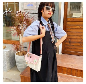 Photo en extérieur d'un petit sac bandoulière en toile avec contraste rose et badges