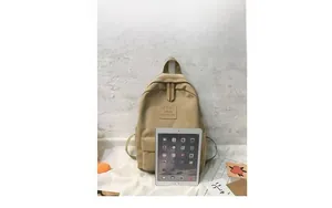 Canvas backpack size comparison with an iPad showing front pocket and logo detail