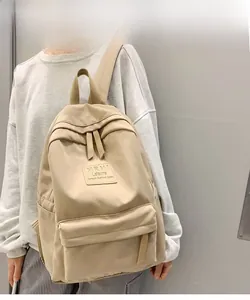 Detailed view of cream-colored casual nylon backpack with front zipper pocket and logo