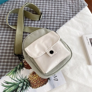 Detail of canvas crossbody bag showing green and beige color blocking with front pocket