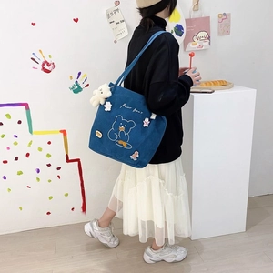 Détail du sac cabas en velours côtelé bleu avec motifs d'ours et breloque peluche