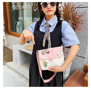 Détail du sac bandoulière en toile rose et blanc avec broderie de dessin animé et fleur