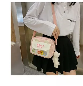 Detail view of pink crossbody bag featuring 3D cat ears and a plush bear charm accessory
