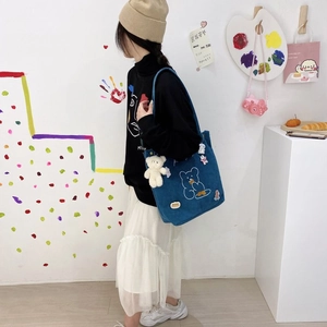 Détail du sac cabas en velours côtelé bleu avec broderie ours et breloque peluche