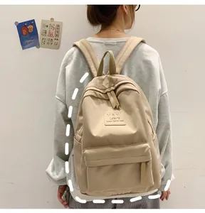 Model wearing a beige minimalist Korean style nylon backpack with leather logo patch