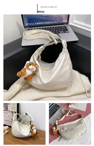 Detailed view of white crescent nylon bag with adjustable strap and plush tiger charm