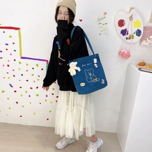 Détail du sac cabas bleu en velours côtelé avec broderie ours et breloque en peluche