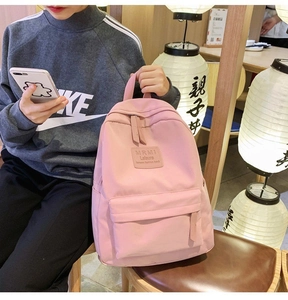 Detailed view of pink nylon backpack featuring high-quality zippers and square leather patch