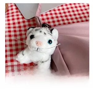 Close-up of white tiger plush pendant with silver chain and blue sequin eyes detail