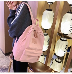 Pink nylon casual backpack for students shown in a cozy indoor lifestyle cafe setting