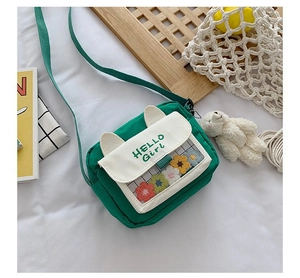 Detail of green canvas crossbody bag with cat ears, transparent window and floral plush decor