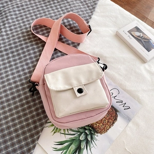 Close-up of pink and white canvas mini crossbody bag with adjustable wide strap and button