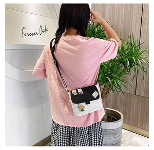 Détail d'un sac bandoulière en toile noir et blanc avec pins de dessin animé sur mannequin