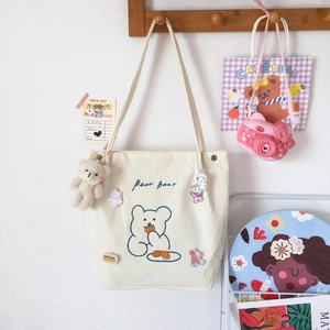 Détail du sac cabas en velours côtelé crème avec broderie d'ours bleu et breloque