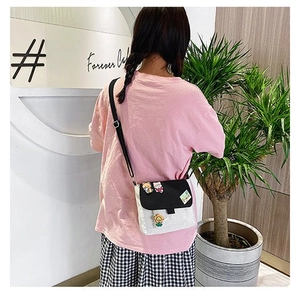Détail du sac bandoulière en toile avec des broches mignonnes et design bicolore