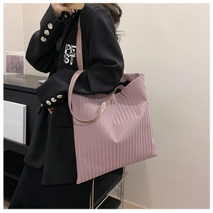 Detailed close-up of pink pleated tote bag fabric texture with metallic snap button closure