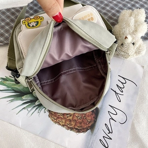 Detail view of mini canvas crossbody bag showing dark nylon interior and pocket