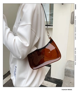 Detail of a brown translucent PVC baguette bag with black zipper and silver metal hooks