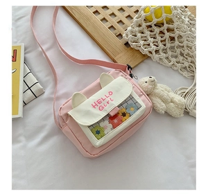 Detail of pink crossbody bag with HELLO Girl print and cute plush bear keychain charm