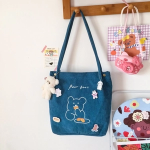 Détail du cabas en velours côtelé bleu avec imprimé ours et badges décoratifs