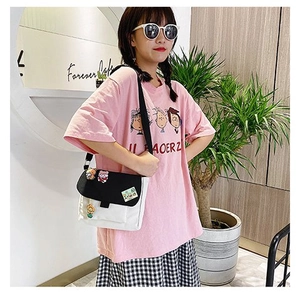 Détail du sac bandoulière en toile contrastée noir et blanc avec des badges mignons