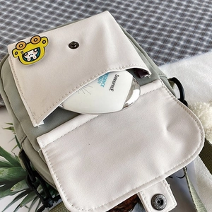 Detail view of mini nylon canvas crossbody bag showing inner pocket and cute cartoon pin