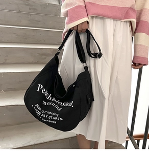 Detail of black canvas tote bag showing white text print and adjustable strap
