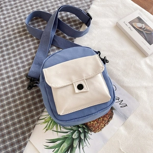 Detail view of mini canvas crossbody bag with blue and beige patchwork and snap closure
