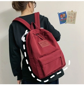 Detail view of the deep red nylon backpack featuring front zipper pocket and MRMI brand logo