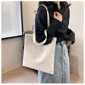 Detailed view of large white corduroy tote bag with texture worn by a model
