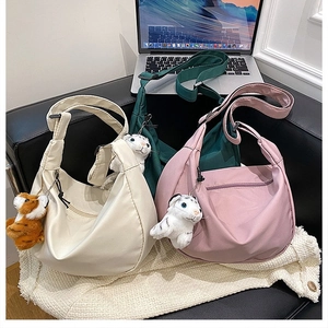 Nylon crescent crossbody bags in cream, green, and pink with plush animal charms