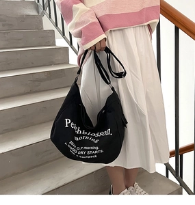 Detail of black canvas tote bag showing white Peachblossom print and adjustable strap