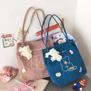 Gros plan de sacs cabas en velours côtelé rose et bleu avec broderie ours et breloque
