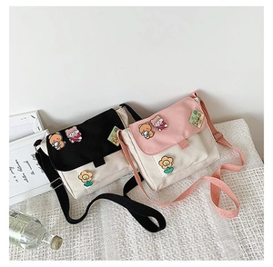 Gros plan de sacs bandoulière en toile avec des broches de dessin animé noir et rose