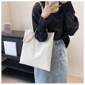 Detail shot of white tote bag featuring unique vertical pleated texture and large capacity