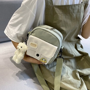 Detail of nylon crossbody bag with cute bear pendant and cartoon car badge decoration
