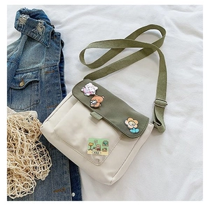 Détail du sac bandoulière en toile avec broderie chat et bandoulière verte réglable