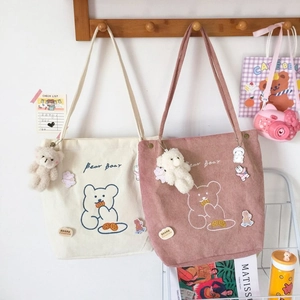 Détail de sacs fourre-tout en velours côtelé avec broderie d'ours et écussons de dessin animé