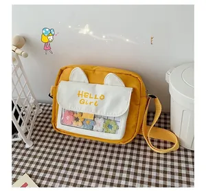 Detail view of yellow canvas crossbody bag featuring cat ears and floral transparent window